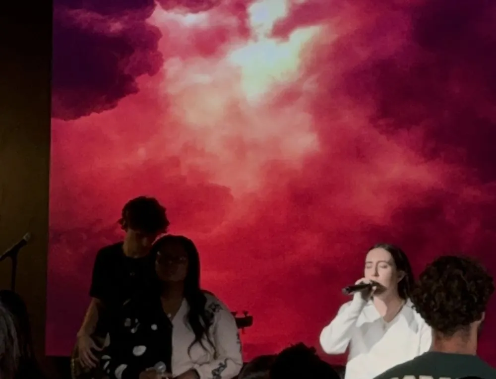 Singer leading worship in front of a red sky backdrop