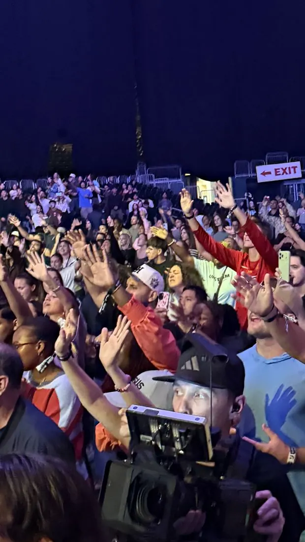Packed arena crowd with a camera operator filming