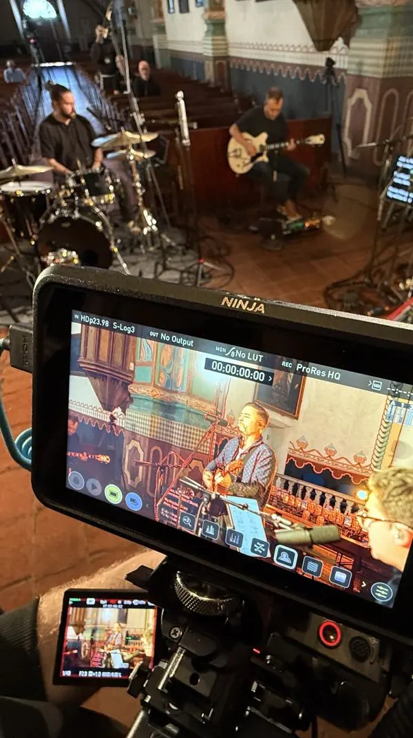 Camera monitor framing a band recording in a historic mission